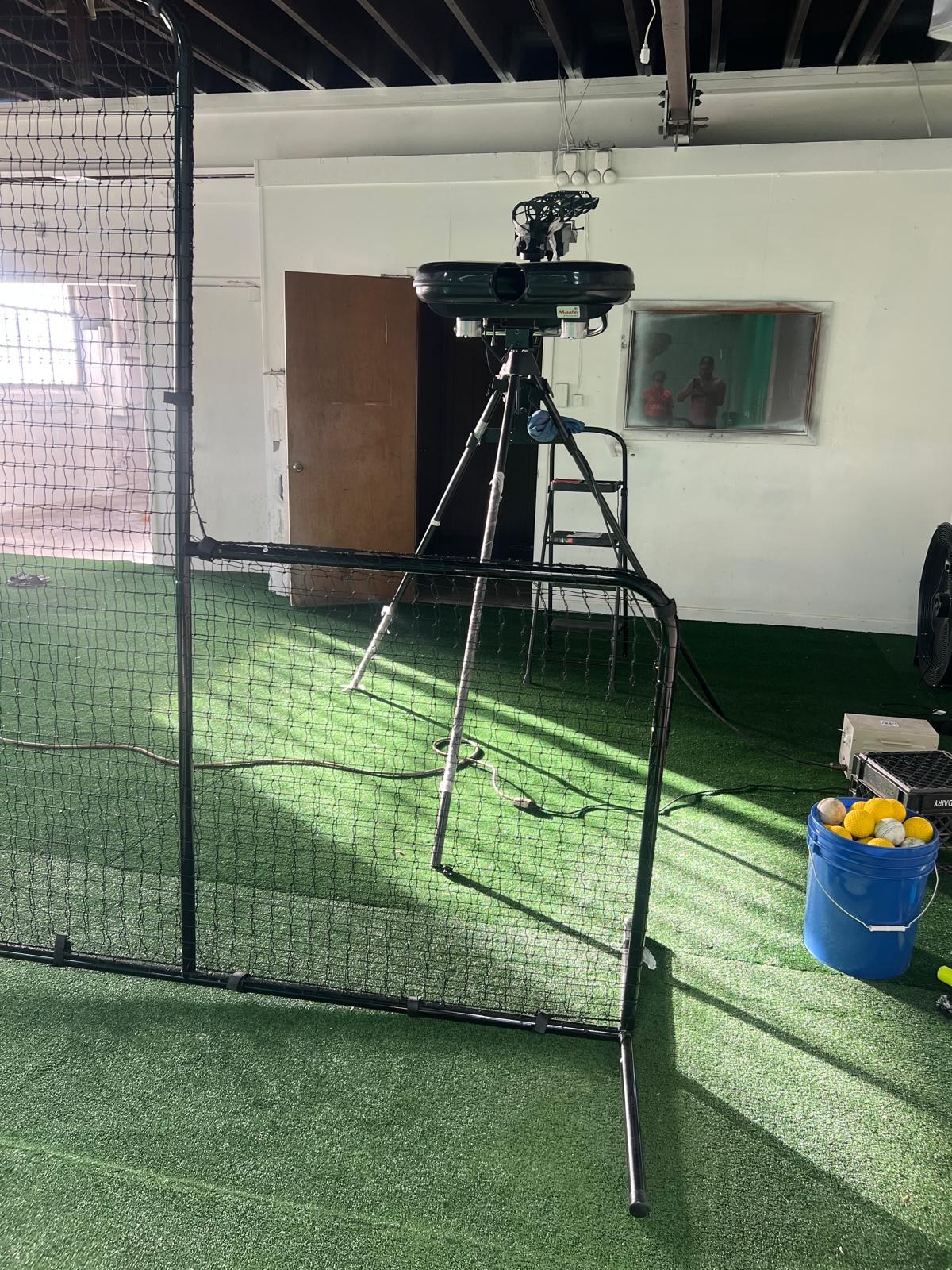 Bowling machine with an overhead ball feeder, protective screen and bucket of practice balls