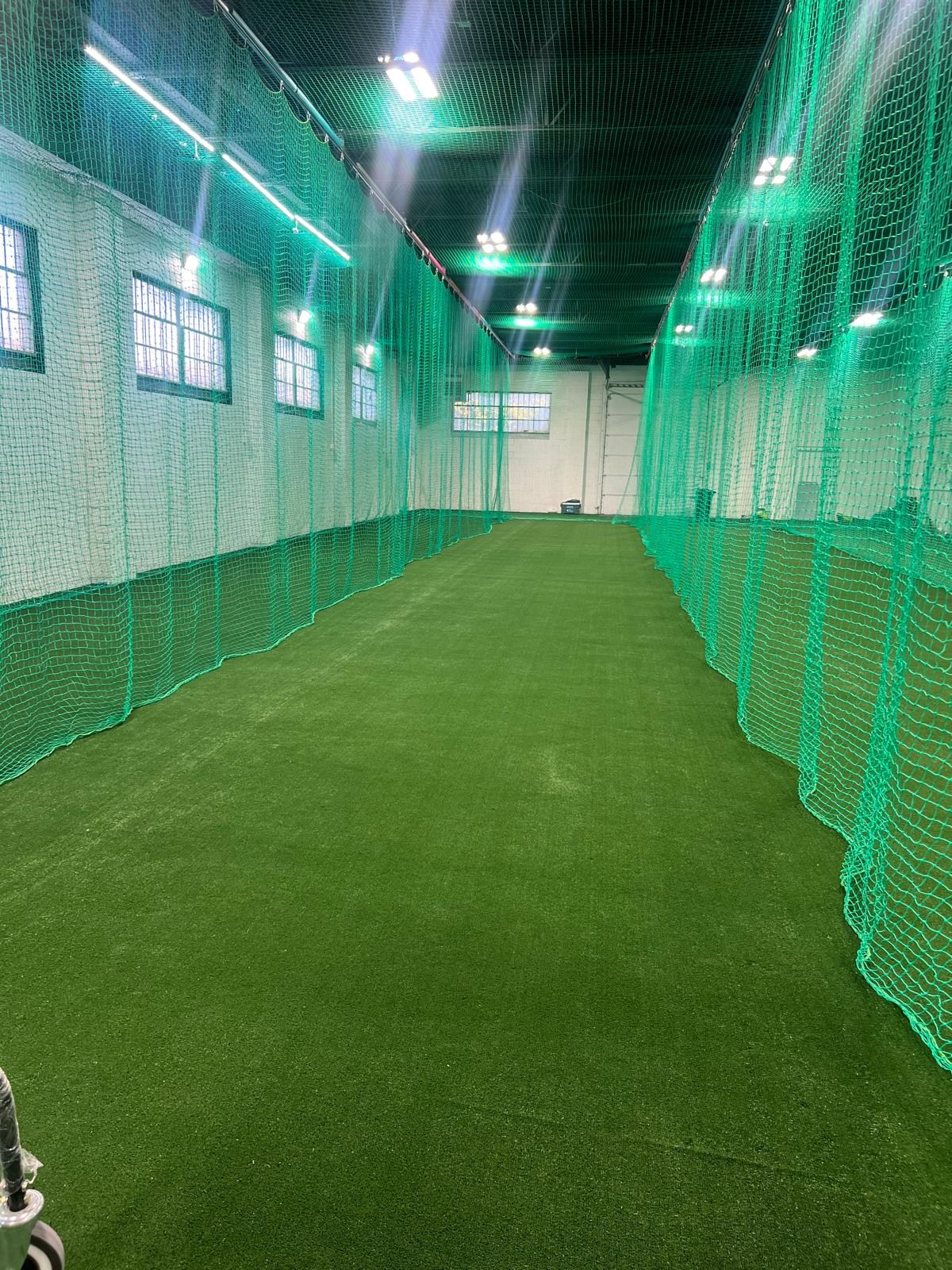 Indoor batting and bowling lane with turf and full-height protective netting